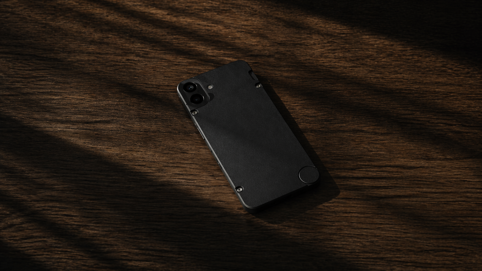 Un teléfono BLANK boca abajo sobre una mesa de madera oscura